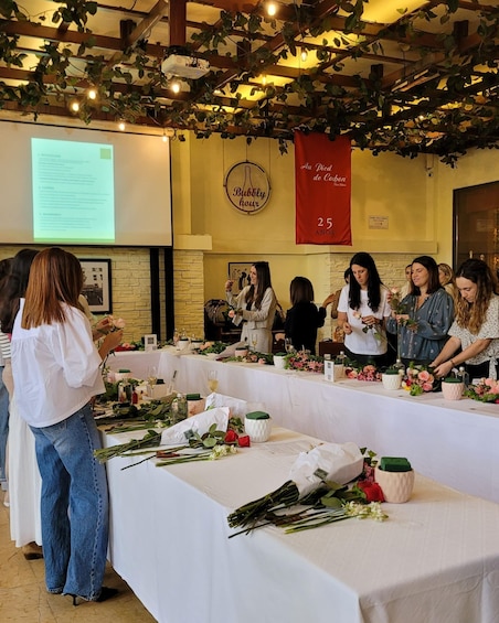 A group of people at a table with flowers and wine glasses, a banner reading '25 ANOS', and a sign that says 'Bubbly hour'. 5