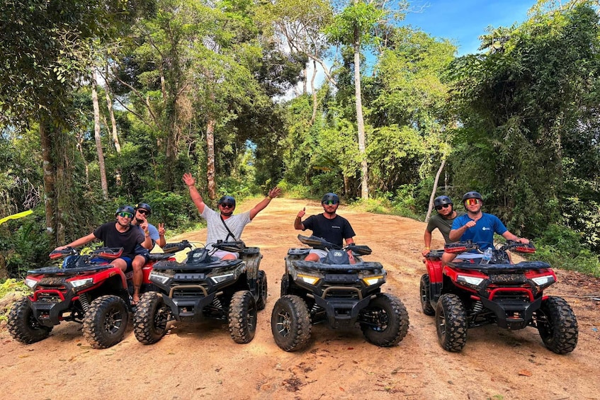 Four people on ATVs on a dirt path surrounded by trees. 3