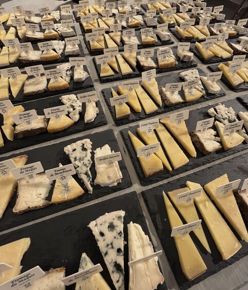 A variety of cheese types displayed on black trays with labels. 2