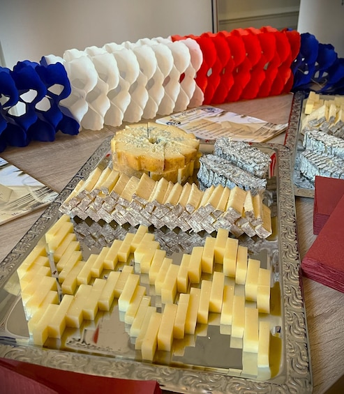 A cheese platter with various types of cheese and decorative paper flowers. 1