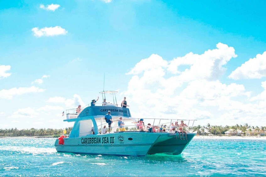 A boat named 'Caribbean Sea II' on clear turquoise waters with a beach and palm trees in the background. 3