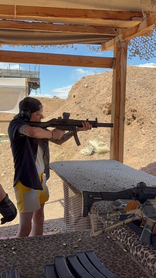 A person aiming a rifle at a shooting range with targets and a desert landscape in the background. 2