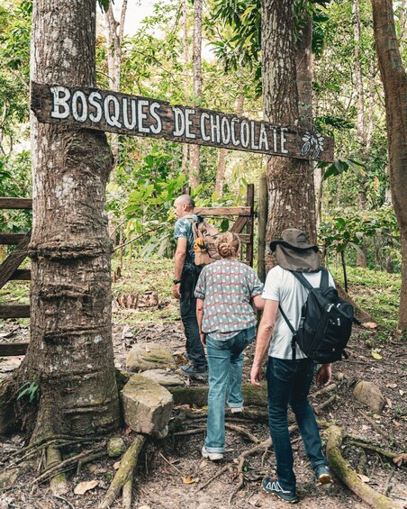 A group of hikers at a trail entrance marked 'BOSQUES DE CHOCOLA.' 5