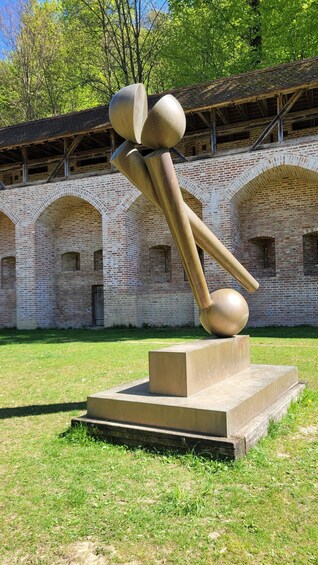 A sculpture in an outdoor setting with a brick building in the background. 1