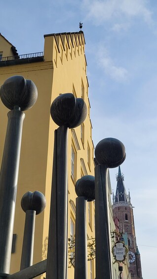 A yellow building with a pointed roof and a clock tower in the background. 2
