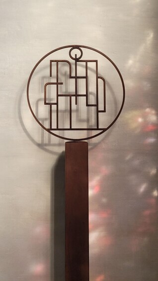 A circular logo with a geometric design on a vertical metal bar. 5