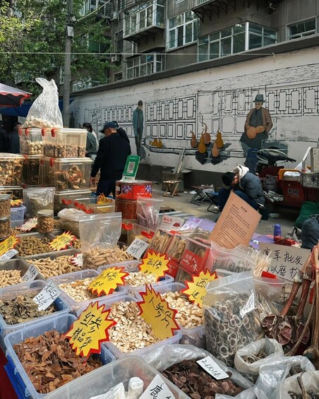 A street market with various food items and a mural in the background. 4