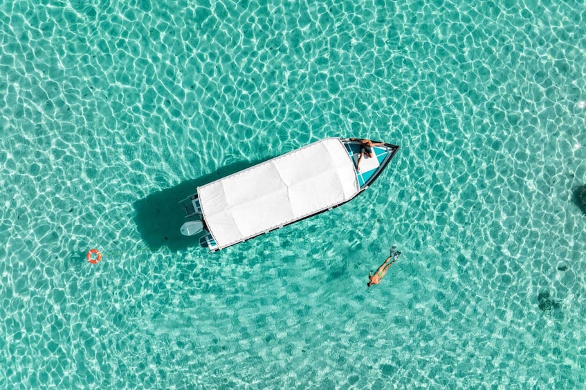 A boat on clear turquoise water with a lifebuoy and a small orange object nearby. 4