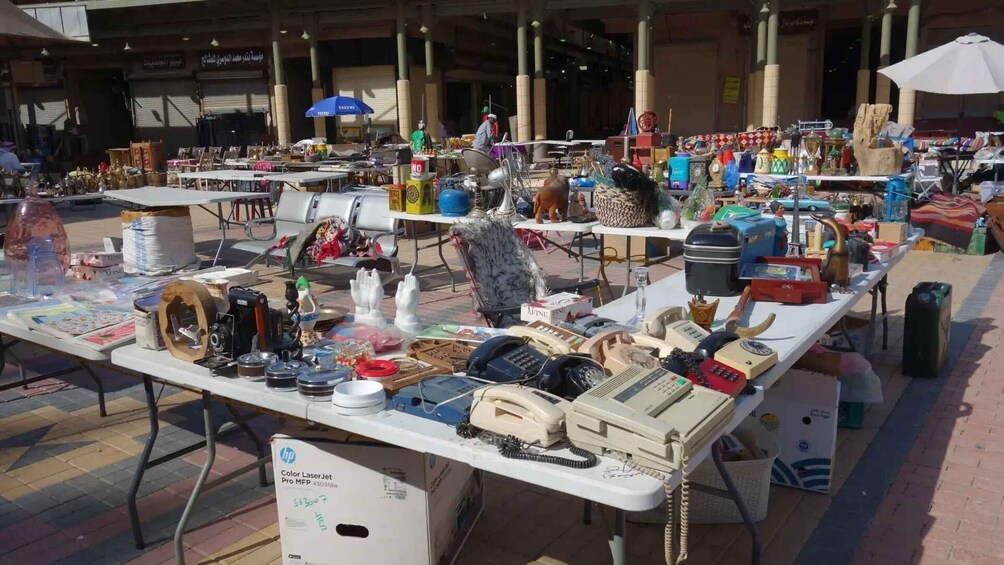 A flea market with various items on tables, including electronics and decorative objects. 4