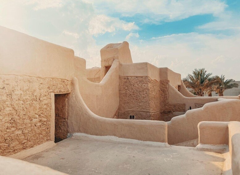 A desert landscape with traditional mud-brick architecture, palm trees, and a clear sky. 5
