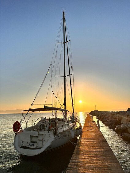 A sailboat docked at a wooden pier during sunset. 3