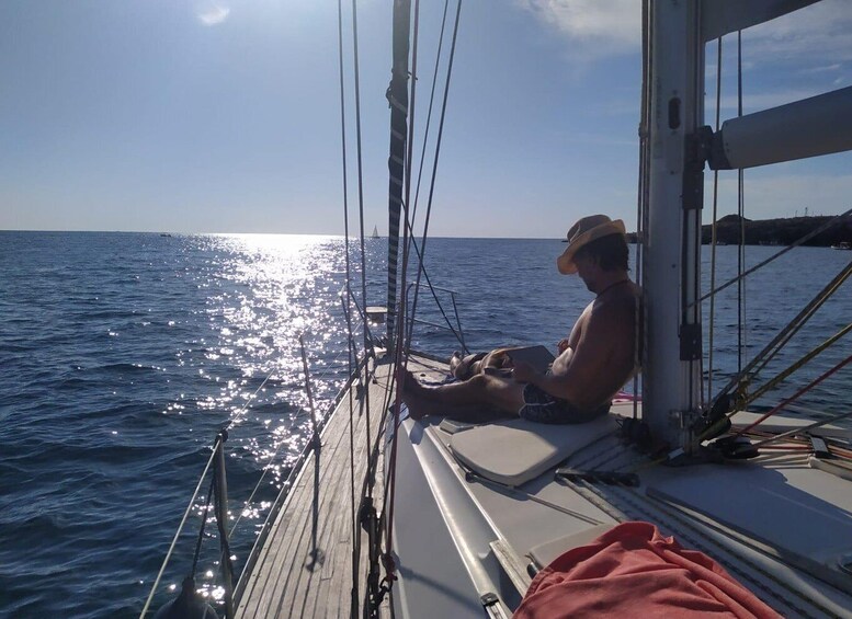 A person sitting on a boat deck, reading a book, with the sun reflecting off the water. 2