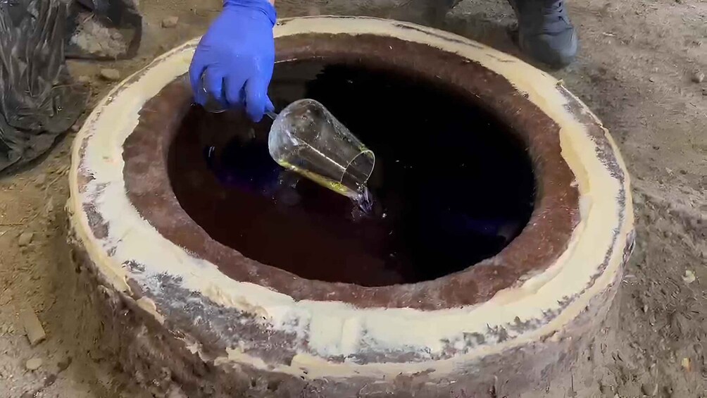 A person pouring a liquid into a large, circular container. 5