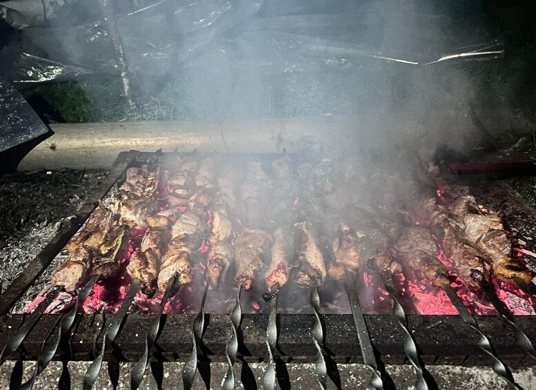 A grill with skewers of meat being cooked over an open flame. 3