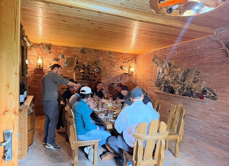 A group of people dining in a rustic brick-walled room with wooden furniture and decorative elements. 5