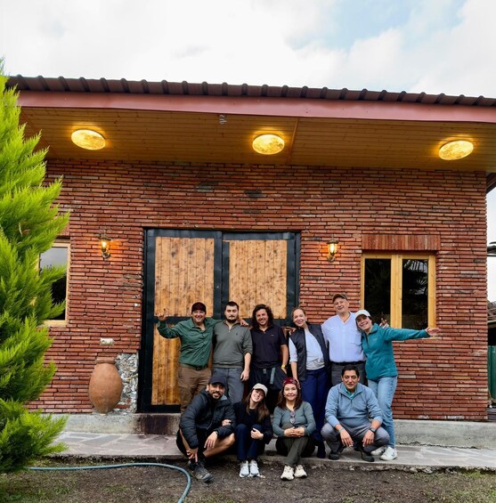 A group of people posing in front of a brick building with a wooden door and a window. 4