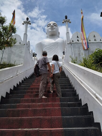 A large white statue at the top of a staircase with flags on either side. 1
