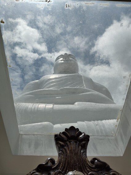 A large, clear glass window with a view of a Buddha statue and a cloudy sky. 2