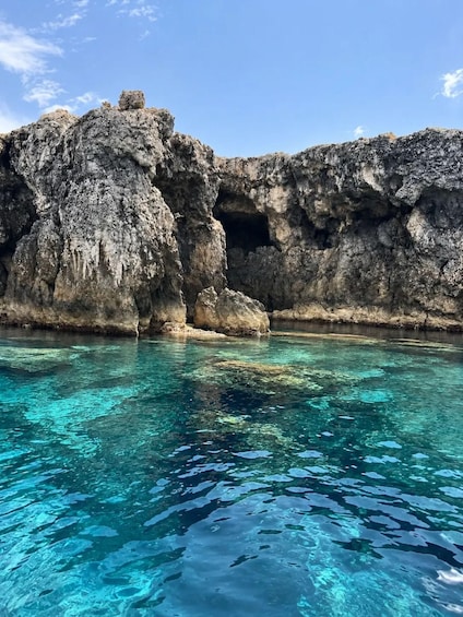 A rocky coastline with clear turquoise waters and a cave entrance. 3