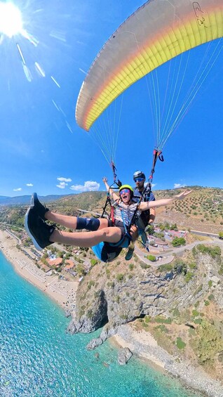 A person paragliding over a coastal area with clear skies and a view of the beach below. 2