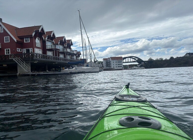 A green kayak on calm water with buildings and a bridge in the background. 5