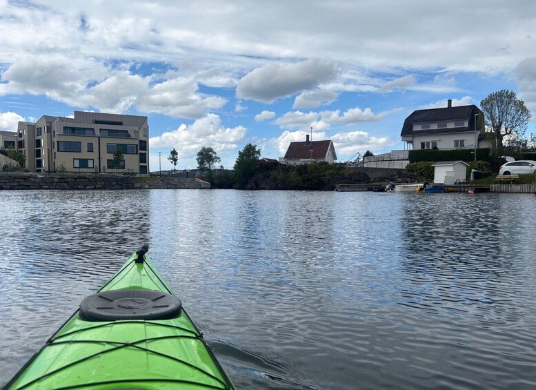 A green kayak on calm water with buildings and trees in the background. 4