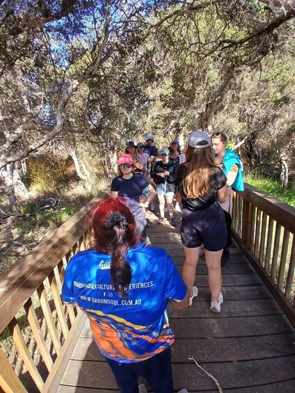 A group of people on a wooden bridge in a wooded area. 2