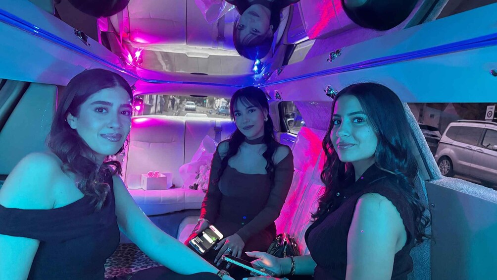 Three people inside a vehicle with colorful lighting. 5