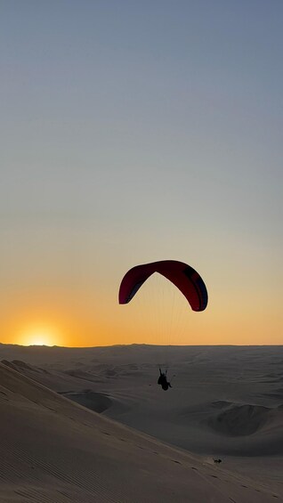 A person paragliding over a desert landscape at sunset. 2