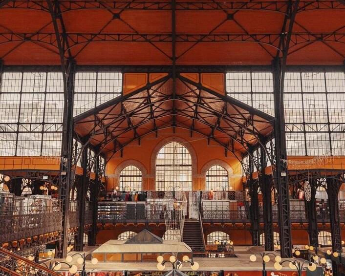 An indoor market with a high ceiling, arched windows, and a central staircase. 4