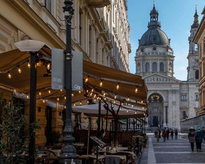 A street with outdoor cafes, a historic building with a dome, and pedestrians. 2