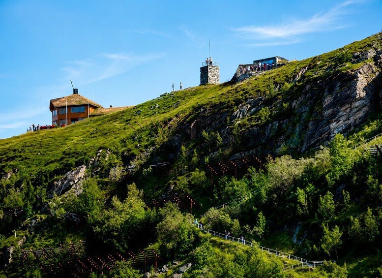 A mountainous landscape with a stone tower, a building with a thatched roof, and a winding path. 3