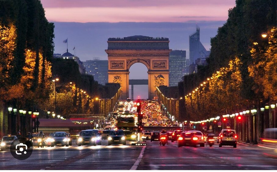A busy street with traffic lights and a large archway in the background. 4