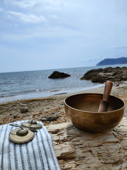 A meditation bowl on a beach with rocks and the sea in the background. 5