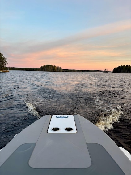 A boat moving through a body of water with a forested shoreline in the background. 2