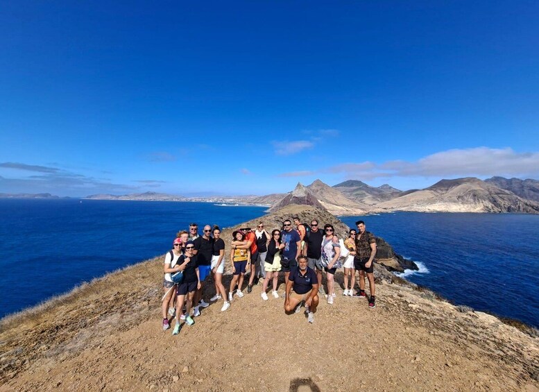A group of people on a rocky cliff overlooking the ocean with mountains in the background. 5
