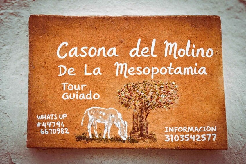 A textured brown sign with white text and illustrations of a cow and a tree, indicating a tour guide service. 1
