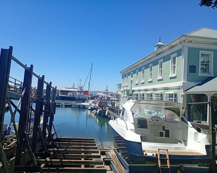 A marina with boats docked, a wooden dock, and a building with a green facade. 1
