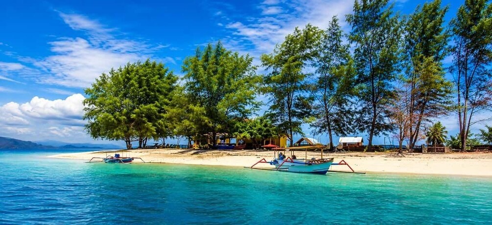A beach with clear turquoise water, a sandy shore, and several boats. 1