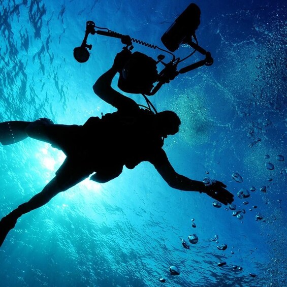 A silhouette of a diver with fins and a scuba tank, swimming underwater. 4