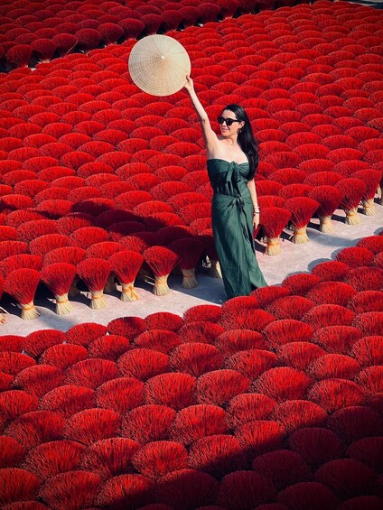 Une personne se tient debout au milieu d’un champ de fleurs rouges, tenant un éventail. 1