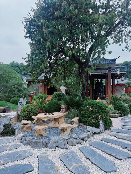 Un pavillon traditionnel, doté d’un toit en tuiles, entouré d’une végétation luxuriante et bordé d’un sentier en pierre. 4
