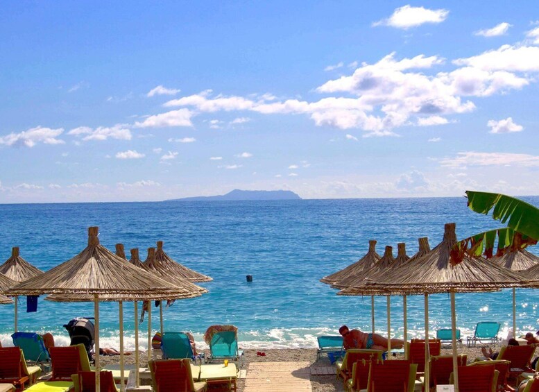 A beach with thatched umbrellas and lounge chairs facing the ocean. 2