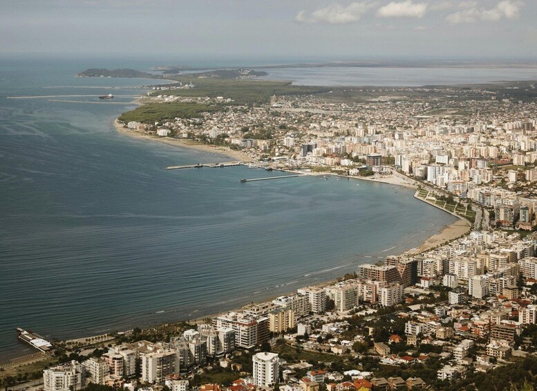 A coastal cityscape with a curved bay, dense urban buildings, and a distant island. 1