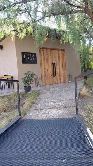 A wooden door with 'GR' and 'GARDEN & RESTO' signs, a potted plant, and a metal staircase leading to a building. 3