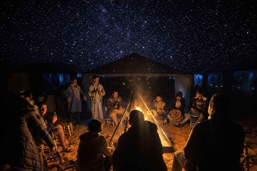 A group of people gathered around a campfire under a starry sky. 2