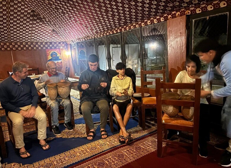 A group of people sitting on chairs in a room with patterned carpet and a ceiling with circular designs. 4