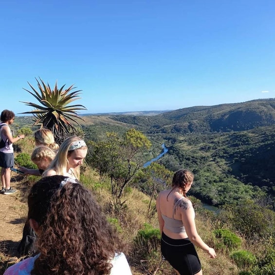 A group of people hiking on a hillside with a river in the valley below. 1