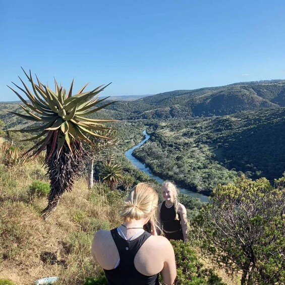 A person standing on a hill overlooking a river and mountains. 4