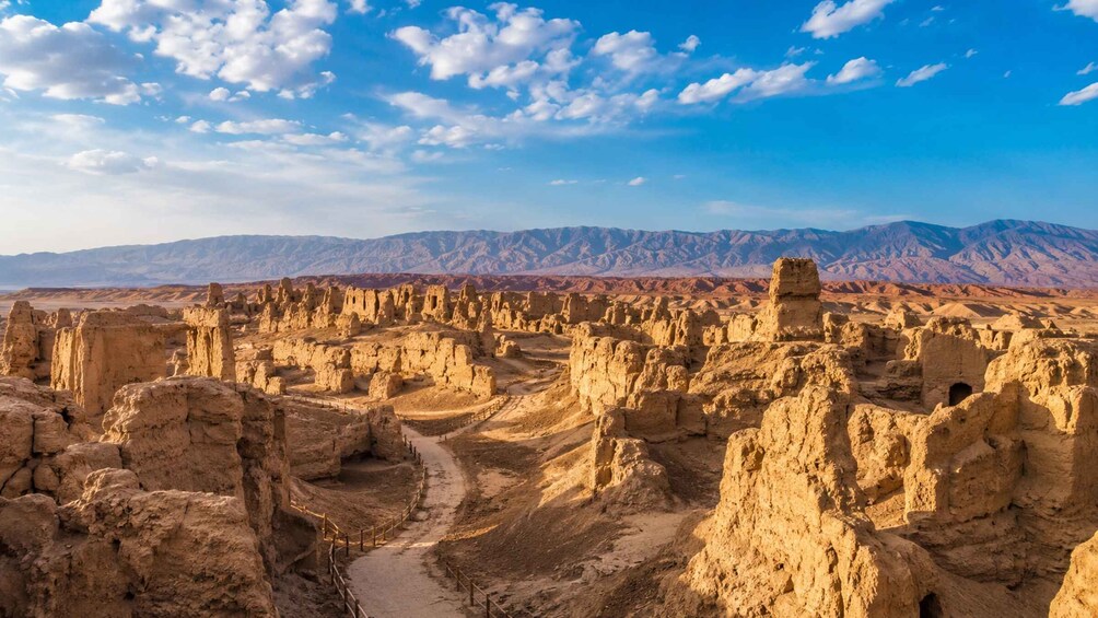 A desert landscape with ancient rock formations and a mountain range in the background. 1